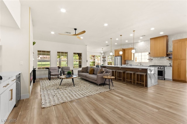 living room featuring baseboards, a ceiling fan, wine cooler, recessed lighting, and light wood finished floors