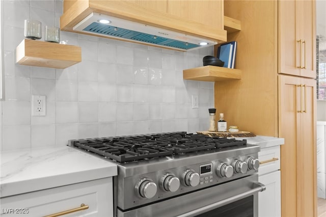 kitchen with open shelves, premium range hood, high end stainless steel range, decorative backsplash, and light stone counters