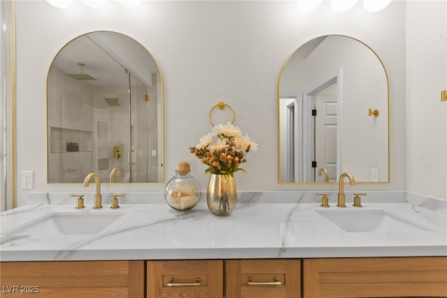 bathroom featuring a shower stall, double vanity, and a sink