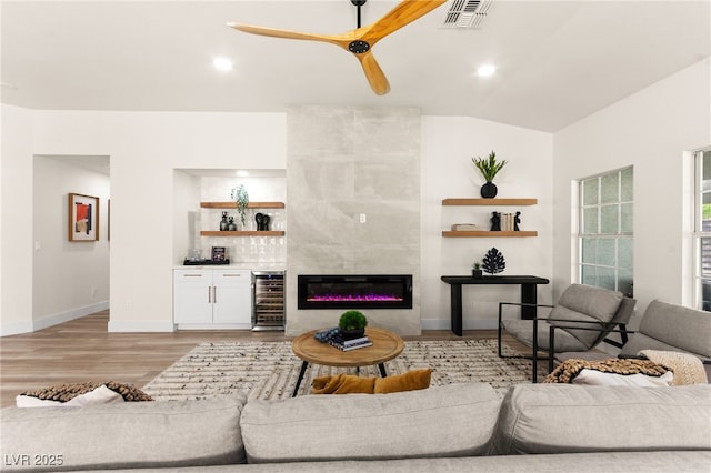 living room featuring visible vents, ceiling fan, a dry bar, light wood-style floors, and wine cooler