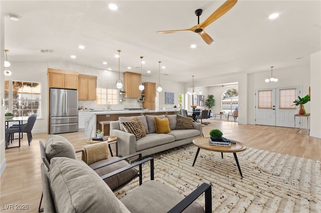 living room with recessed lighting, light wood finished floors, visible vents, and ceiling fan with notable chandelier