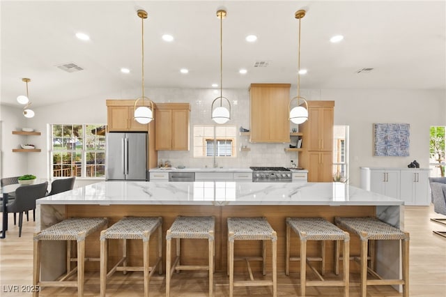 kitchen with visible vents, a sink, appliances with stainless steel finishes, vaulted ceiling, and decorative backsplash