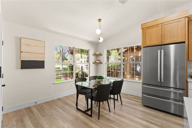 dining room featuring light wood-style flooring, baseboards, and vaulted ceiling