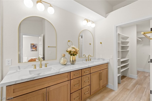 full bathroom with a sink, double vanity, connected bathroom, and wood finished floors