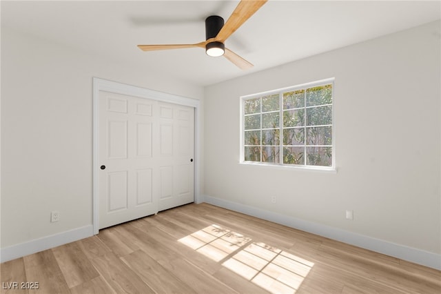 unfurnished bedroom featuring light wood-style flooring, a ceiling fan, and baseboards