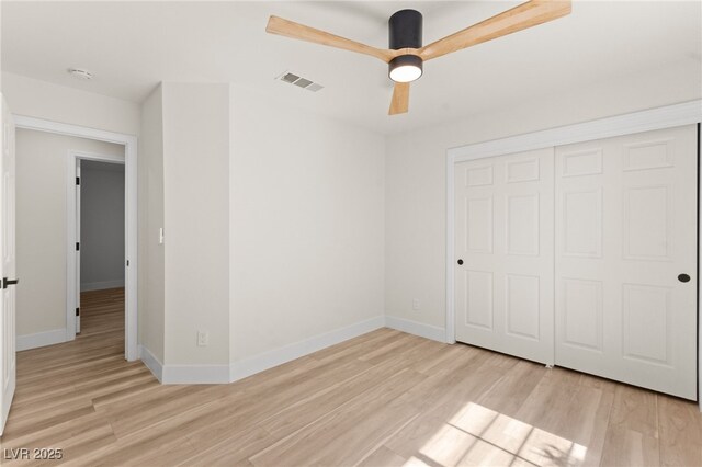 unfurnished bedroom with light wood-style flooring, a closet, baseboards, and visible vents