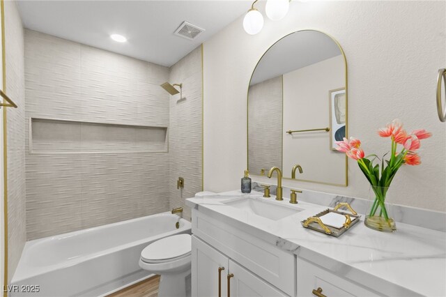 bathroom with vanity, visible vents, toilet, wood finished floors, and shower / bathing tub combination