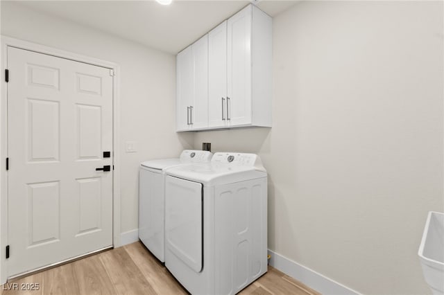 laundry room featuring light wood-style floors, separate washer and dryer, baseboards, and cabinet space