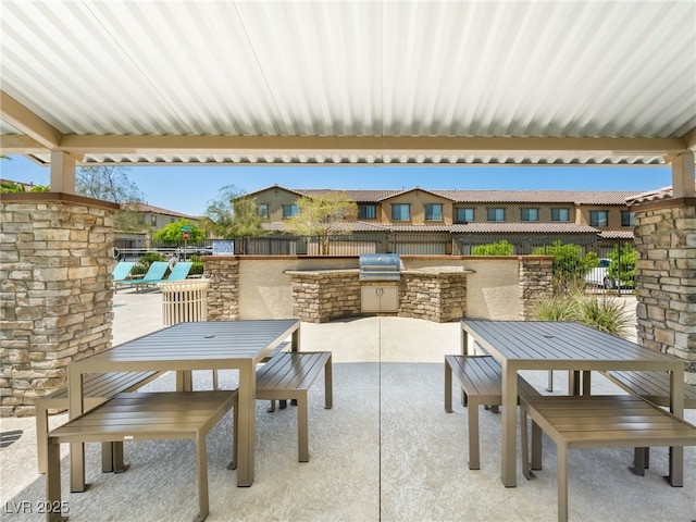 view of patio with a grill, outdoor dining area, an outdoor kitchen, and fence