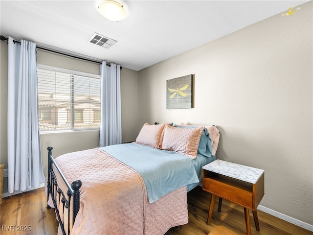 bedroom featuring visible vents, baseboards, and wood finished floors
