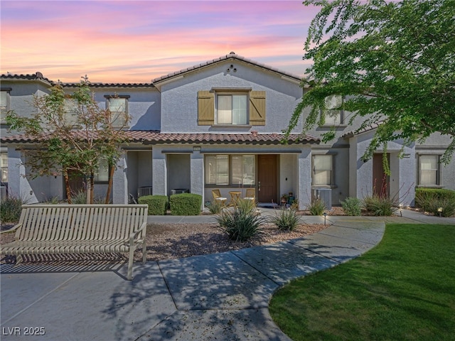 mediterranean / spanish house featuring a tiled roof and stucco siding