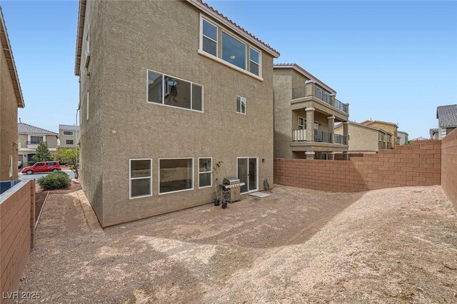 rear view of property with stucco siding and fence