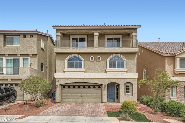 view of front of house featuring a balcony, stucco siding, decorative driveway, and an attached garage