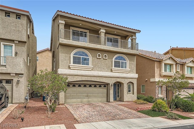 view of front of property with an attached garage, a balcony, stucco siding, and decorative driveway