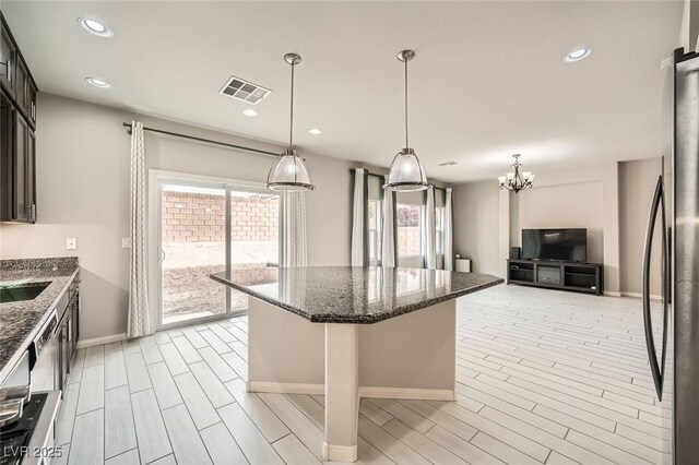 kitchen featuring dark stone counters, freestanding refrigerator, visible vents, a center island, and wood tiled floor