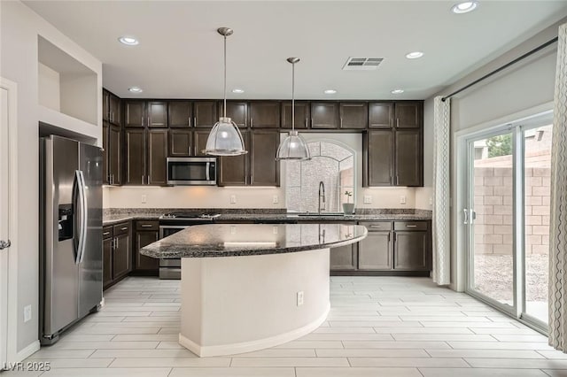 kitchen featuring dark stone counters, appliances with stainless steel finishes, visible vents, and dark brown cabinetry