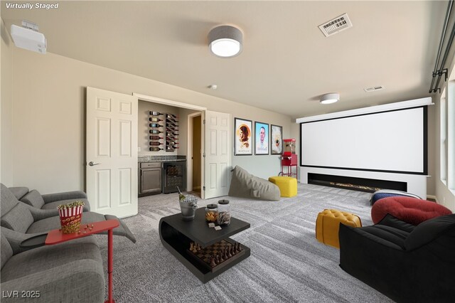 cinema room with wine cooler, visible vents, a dry bar, and light colored carpet