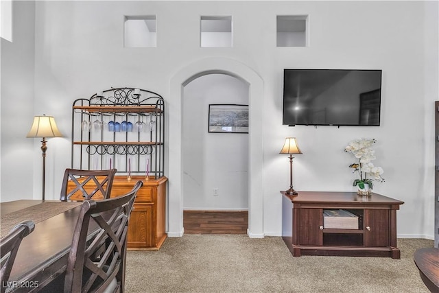carpeted office space with baseboards and arched walkways
