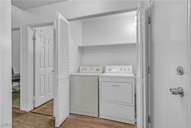 laundry area with washing machine and dryer, wood finished floors, and laundry area