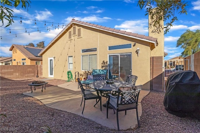 rear view of house featuring a tiled roof, a fire pit, a fenced backyard, a patio, and stucco siding