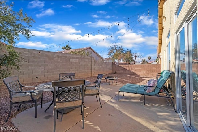 view of patio / terrace with a fire pit, outdoor dining space, and a fenced backyard