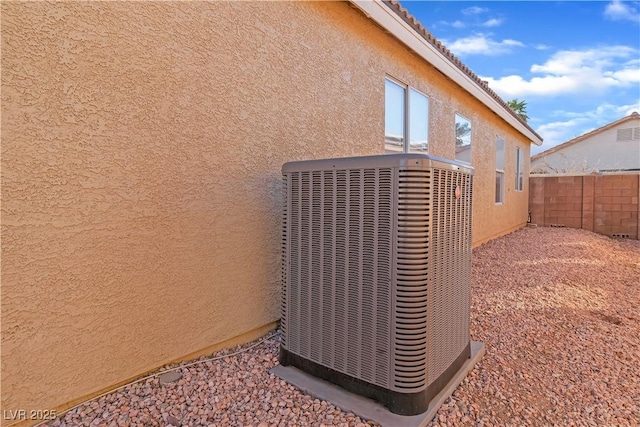 exterior details with central air condition unit, stucco siding, and fence
