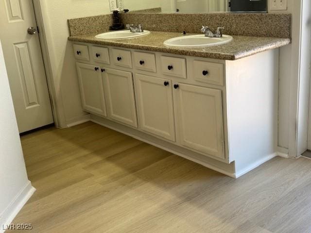 full bath with baseboards, wood finished floors, and a sink
