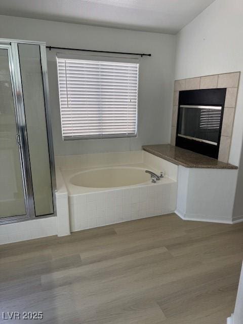 bathroom with a bath, wood finished floors, and a stall shower