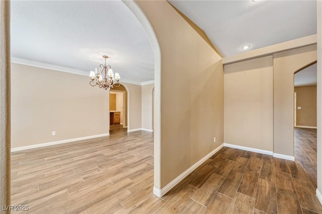 2681 Underbrush Ave, Pahrump, NV 89048 - unfurnished room with baseboards, arched walkways, wood finished floors, and an inviting chandelier