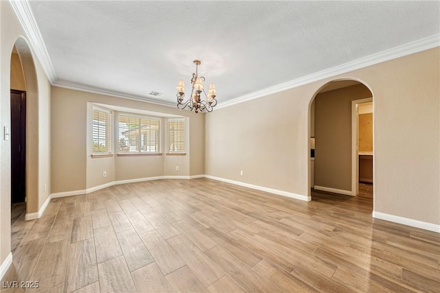 2681 Underbrush Ave, Pahrump, NV 89048 - empty room featuring light wood finished floors, an inviting chandelier, arched walkways, and ornamental molding