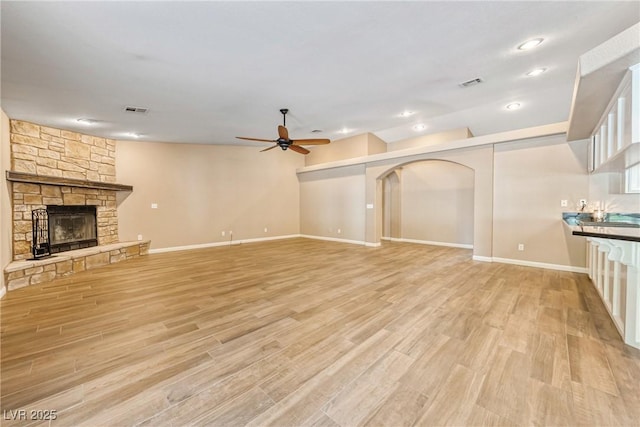 2681 Underbrush Ave, Pahrump, NV 89048 - unfurnished living room featuring light wood-style flooring, baseboards, visible vents, a ceiling fan, and a fireplace