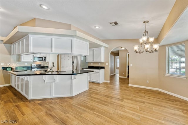 2681 Underbrush Ave, Pahrump, NV 89048 - kitchen with arched walkways, stainless steel appliances, baseboards, white cabinets, and a peninsula