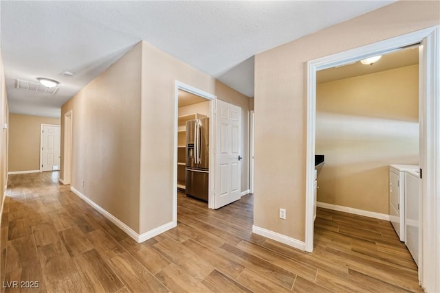 2681 Underbrush Ave, Pahrump, NV 89048 - hallway with washing machine and dryer, light wood-type flooring, visible vents, and baseboards