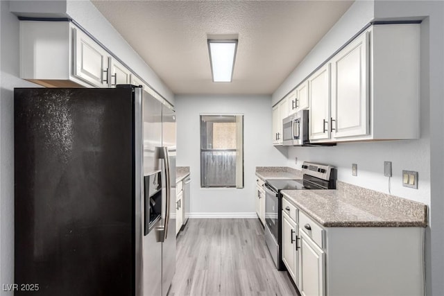 2451 N Rainbow Blvd Unit 1016, Las Vegas, NV 89108 - kitchen with appliances with stainless steel finishes, light wood-style floors, white cabinets, baseboards, and a textured ceiling