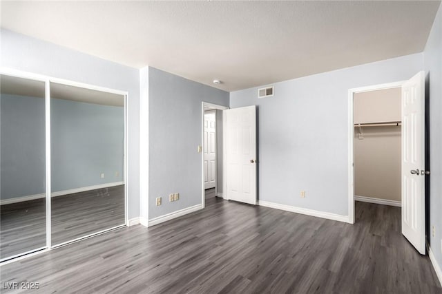 2451 N Rainbow Blvd Unit 1016, Las Vegas, NV 89108 - unfurnished bedroom with dark wood-style flooring, a closet, baseboards, and a walk in closet