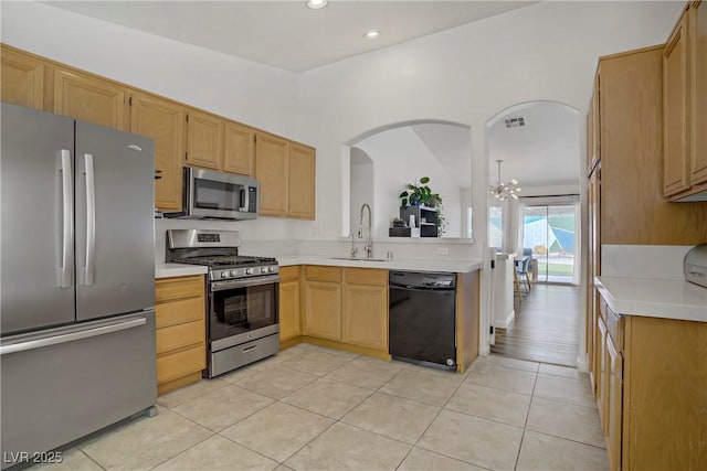 1830 Ginger Blossom Ave, North Las Vegas, NV 89031 - kitchen featuring stainless steel appliances, a sink, light countertops, light tile patterned floors, and arched walkways