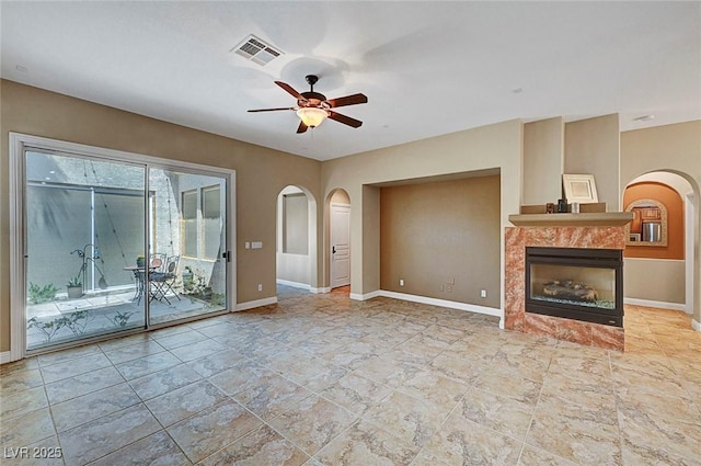 519 Via Garofano Ave, Henderson, NV 89011 - unfurnished living room featuring arched walkways, ceiling fan, a tiled fireplace, and baseboards