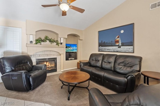 living room with visible vents, ceiling fan, vaulted ceiling, a fireplace with flush hearth, and tile patterned floors