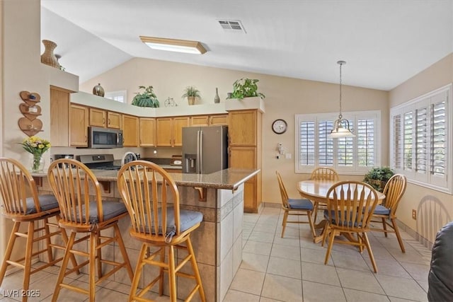 kitchen featuring visible vents, a breakfast bar, a peninsula, a healthy amount of sunlight, and stainless steel appliances