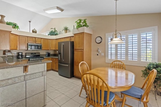kitchen with pendant lighting, light tile patterned floors, light stone countertops, vaulted ceiling, and stainless steel appliances