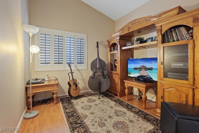 interior space featuring wood finished floors, baseboards, and vaulted ceiling