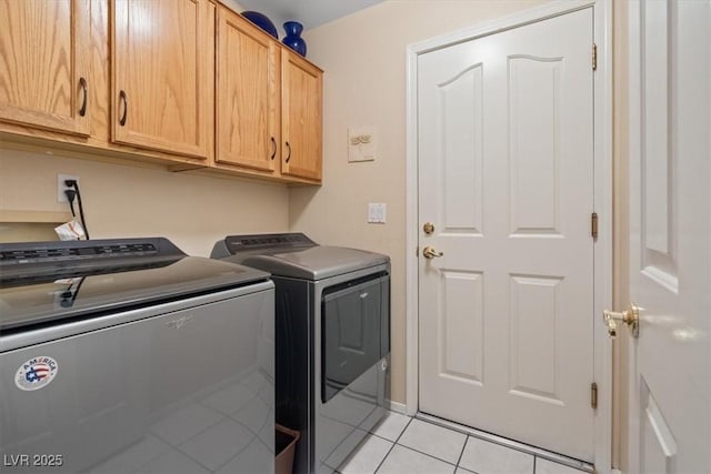 washroom featuring cabinet space, light tile patterned floors, and washing machine and clothes dryer