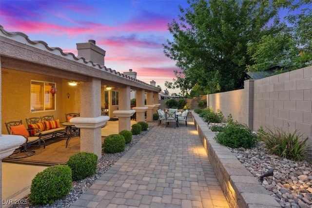 patio terrace at dusk featuring a fenced backyard and an outdoor hangout area