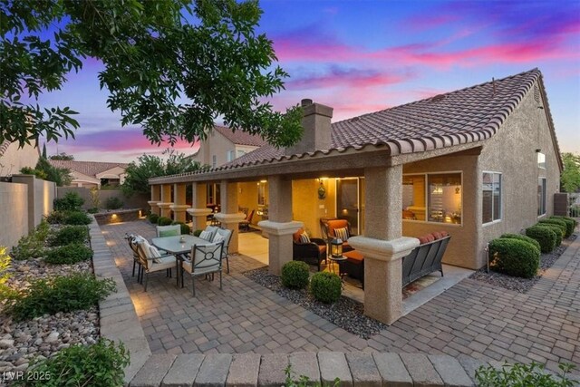 patio terrace at dusk featuring outdoor dining area and fence