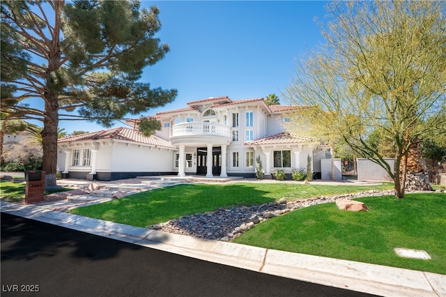 mediterranean / spanish-style home with stucco siding, a gate, a balcony, and a front yard