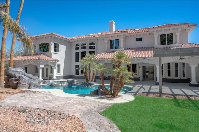 rear view of house with a tile roof, a chimney, a ceiling fan, a patio, and stucco siding