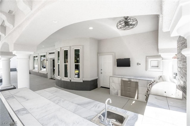 interior space featuring arched walkways, visible vents, and ornate columns