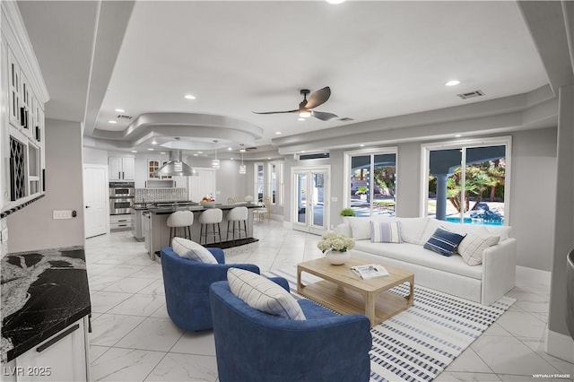 living area featuring recessed lighting, marble finish floor, a raised ceiling, visible vents, and ceiling fan