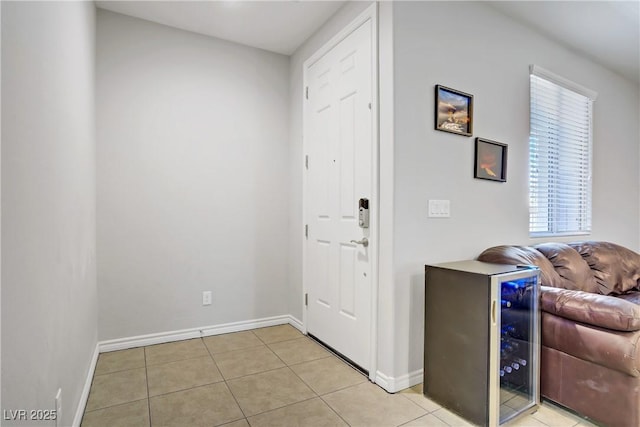 entryway featuring baseboards, light tile patterned floors, and wine cooler