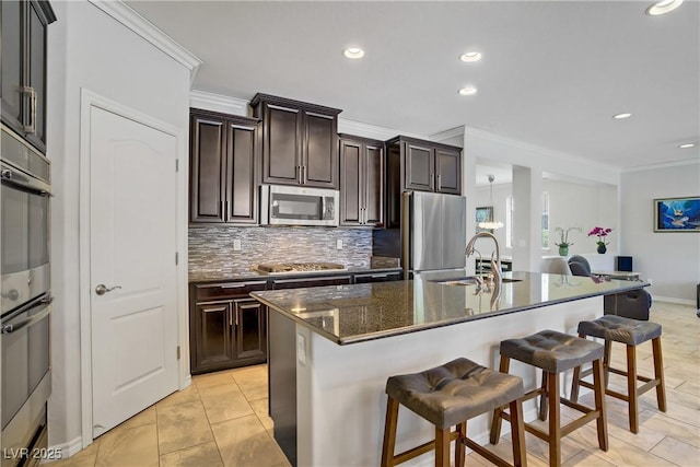 kitchen featuring a breakfast bar area, backsplash, crown molding, a sink, and stainless steel appliances